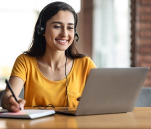 Smiling young woman on her laptop and taking notes.