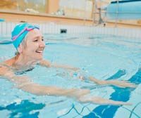 Older woman in swim cap exercising in pool.