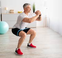 Middle-aged man doing squats in home setting.