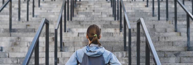 Young woman, hands on hips facing long stairways.