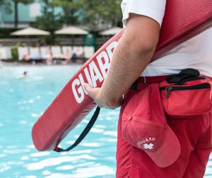 View of the pool in background, looking past lifeguard’s elbow and rescue tube in foreground.