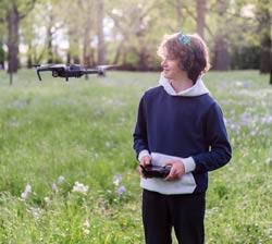 Teenager holder drone control with drone hovering in front of him.