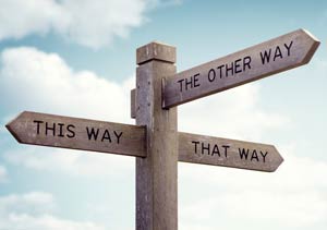 Wooden street sign using arrows to point “THIS WAY,” “THAT WAY” and “THE OTHER WAY.”