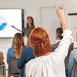 Businesswoman raising her hand to ask a question during a presentation.