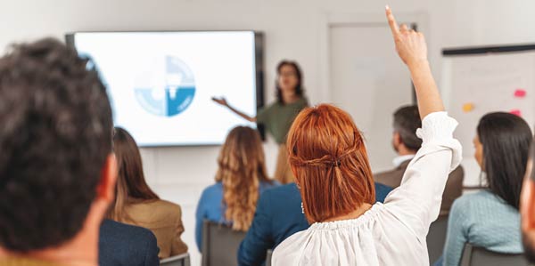 Businesswoman raising her hand to ask a question during a presentation.