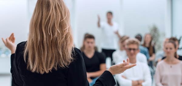 Businesswoman raising her hand to ask a question during a presentation.